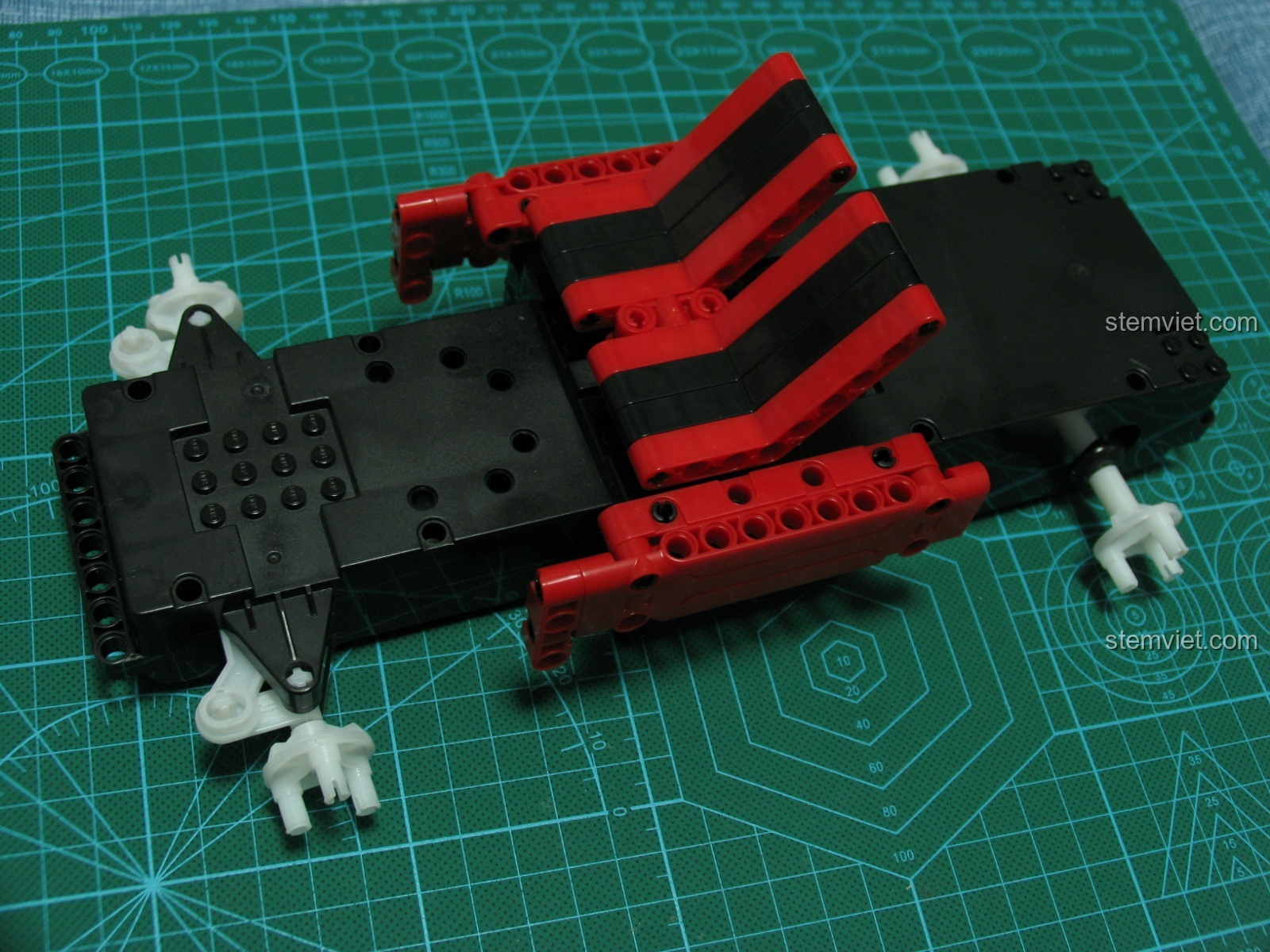 Bắt đầu quá trình lắp ráp phần thân xe bán tải CaDA C51005 trên khung gầm, với các mảnh ghép màu đỏ và đen.