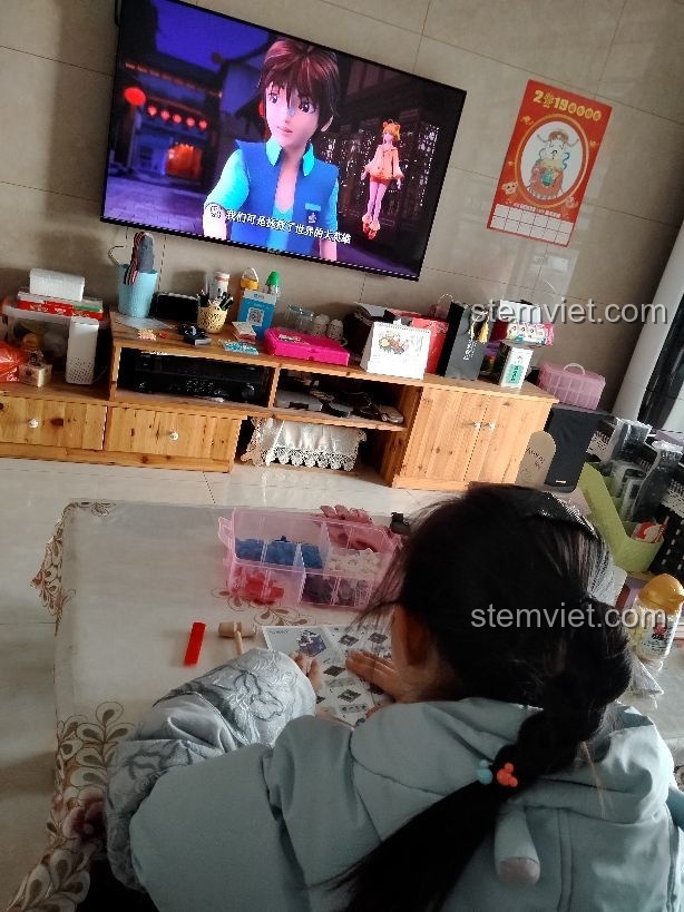 Bé gái 6 tuổi đang tập trung lắp ráp bộ đồ chơi mô hình Cửa hàng nước có ga 6027 một cách say sưa.