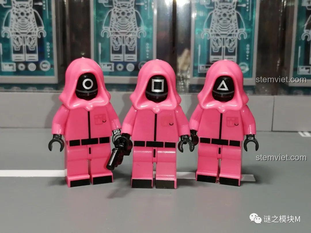 Bộ ba minifigure lính gác Squid Game với mặt nạ hình tròn, vuông và tam giác đứng cạnh nhau.
