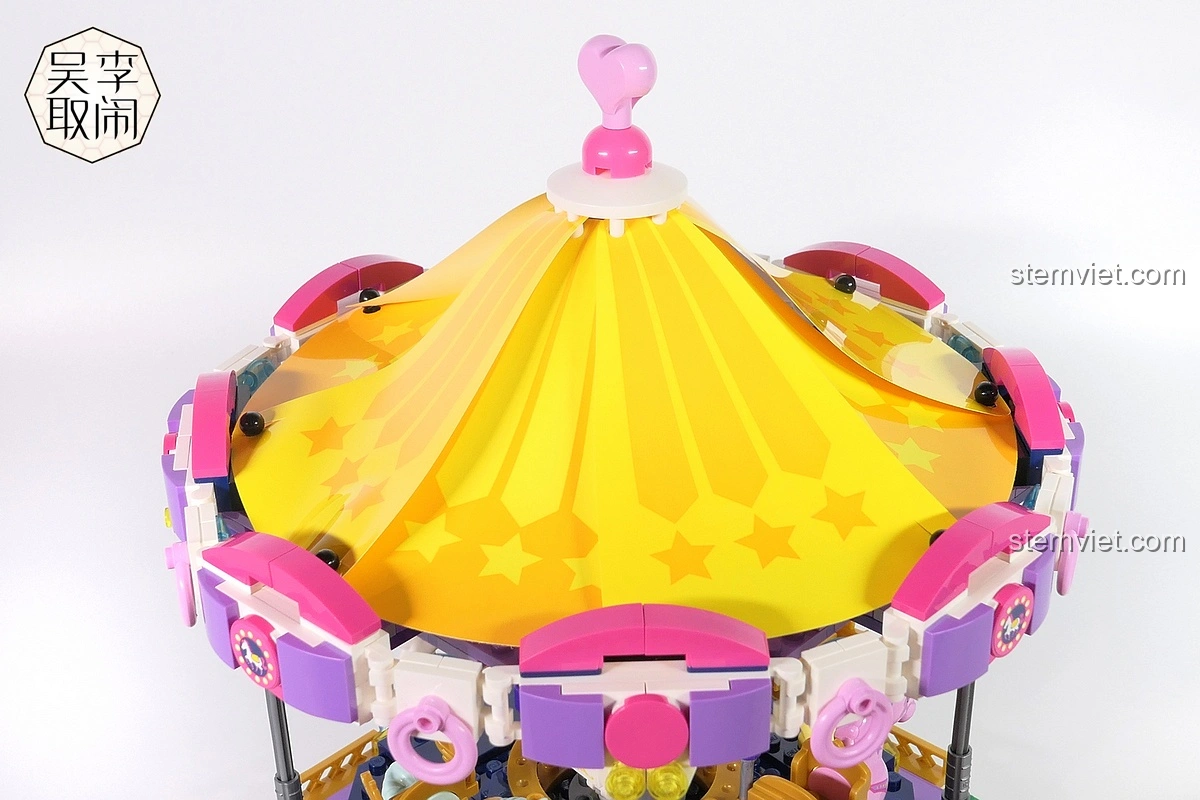 Chi tiết mái nhà quầy vé với các mảnh ghép màu hồng và xanh lá cây trong bộ Vòng Quay Ngựa Gỗ Mộng Mơ Enlighten 2016.