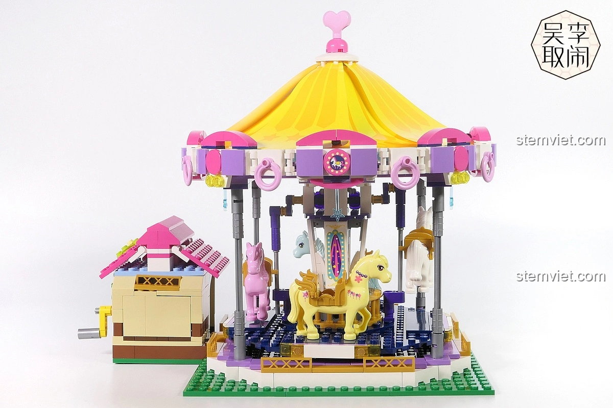 Cận cảnh quầy bán vé của bộ lắp ráp Vòng Quay Ngựa Gỗ Mộng Mơ Enlighten 2016, với mái hồng và biểu tượng.