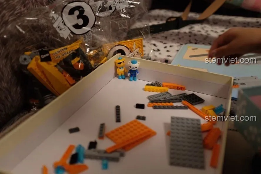 Các chi tiết và hai nhân vật minifigure của bộ đồ chơi Tàu Độc Giác Kình GUP-S QMAN 3704 được sắp xếp trong hộp.