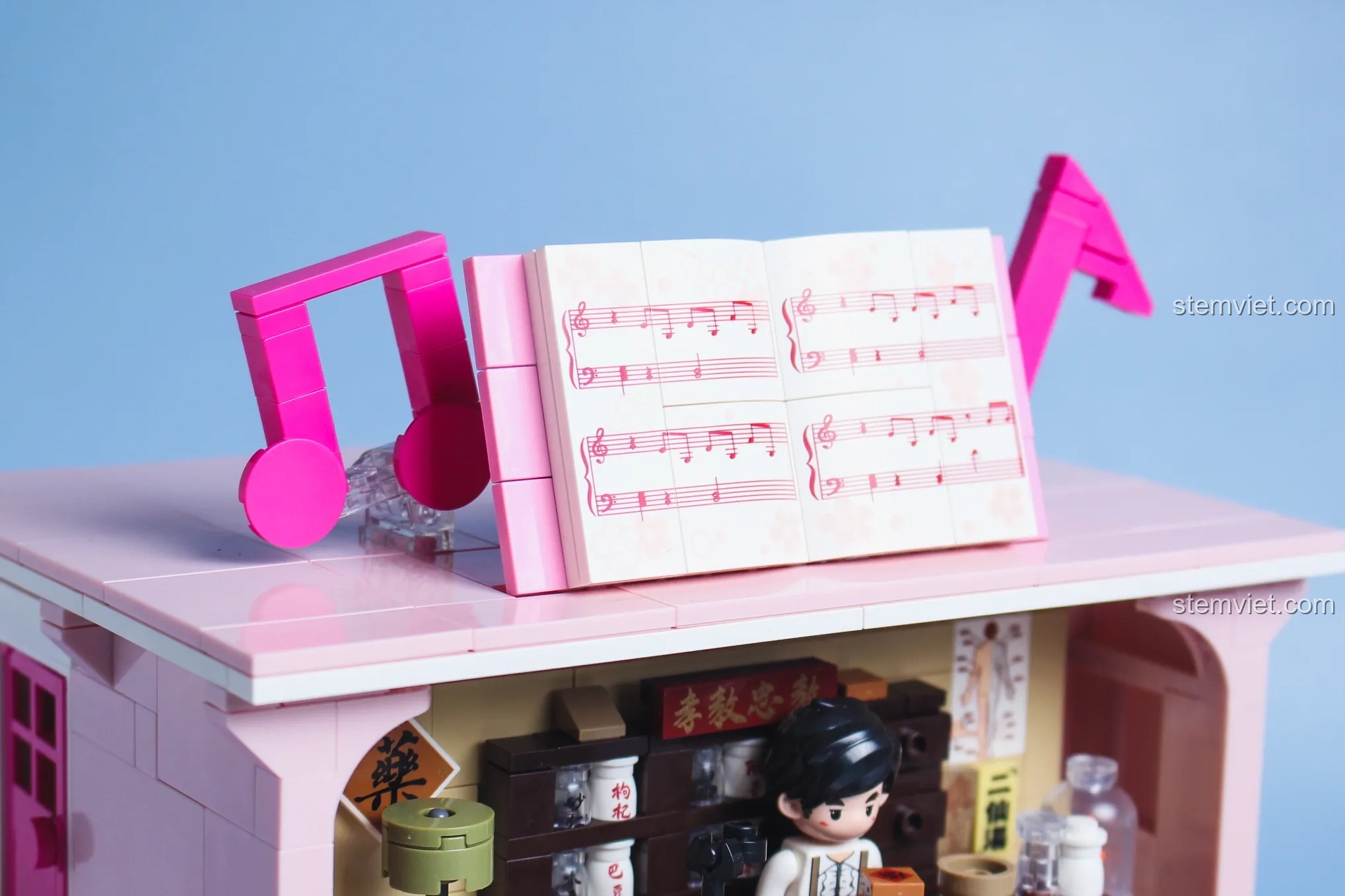 Cận cảnh phần nóc đàn piano Keeppley DZ0155 với bản nhạc và các nốt nhạc trang trí màu hồng.