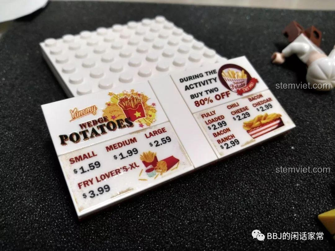 Cận cảnh việc dán sticker menu lên mảnh ghép của bộ đồ chơi mô hình quầy khoai tây chiên Sembo 601058.