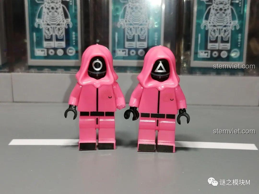 Hai minifigure lính gác Squid Game màu hồng với mặt nạ hình tròn và tam giác, chỉ có chi tiết in ở mặt trước.