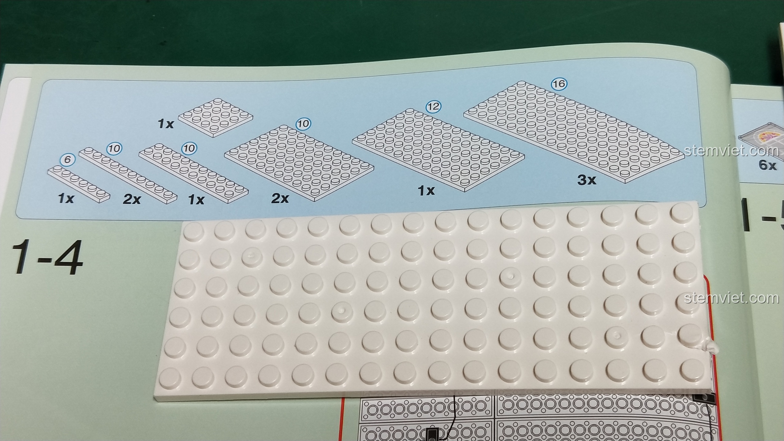 Sách hướng dẫn lắp ráp bộ XINGBAO 1202 và một mảnh ghép plate 6x16 màu trắng bị lỗi, cong vênh ở một góc.