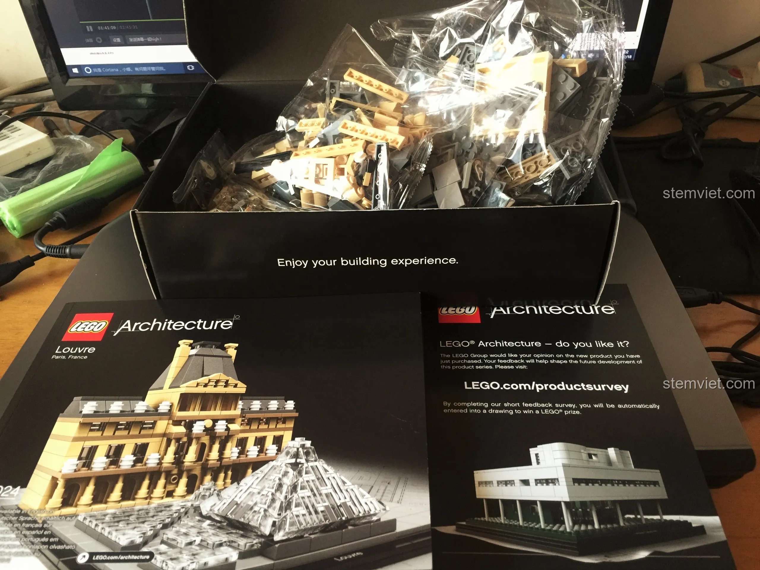 Bên trong hộp LEGO 21024 Louvre gồm các túi mảnh ghép không đánh số và sách hướng dẫn lắp ráp bìa đen sang trọng.