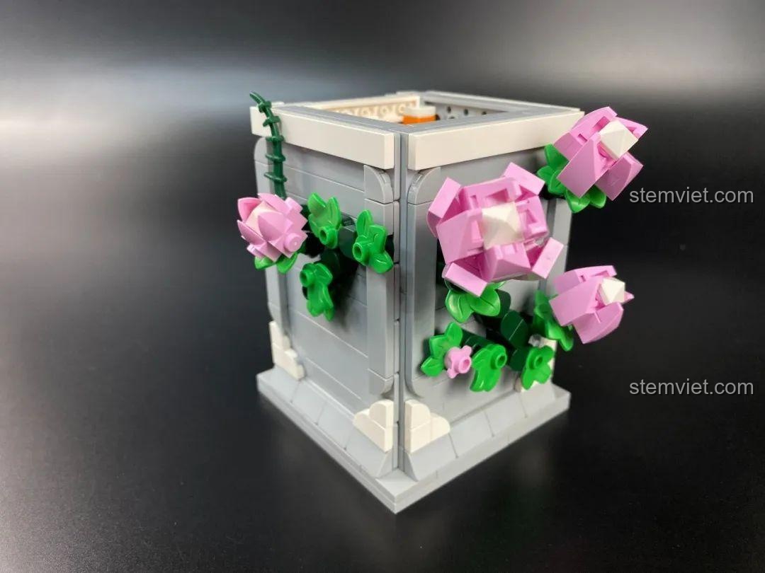 Cận cảnh một bông hoa hồng màu hồng trên phần đế của bộ lắp ráp DOKI 846681 Tượng Thần Tình Yêu Cupid, thể hiện chi tiết tinh xảo.