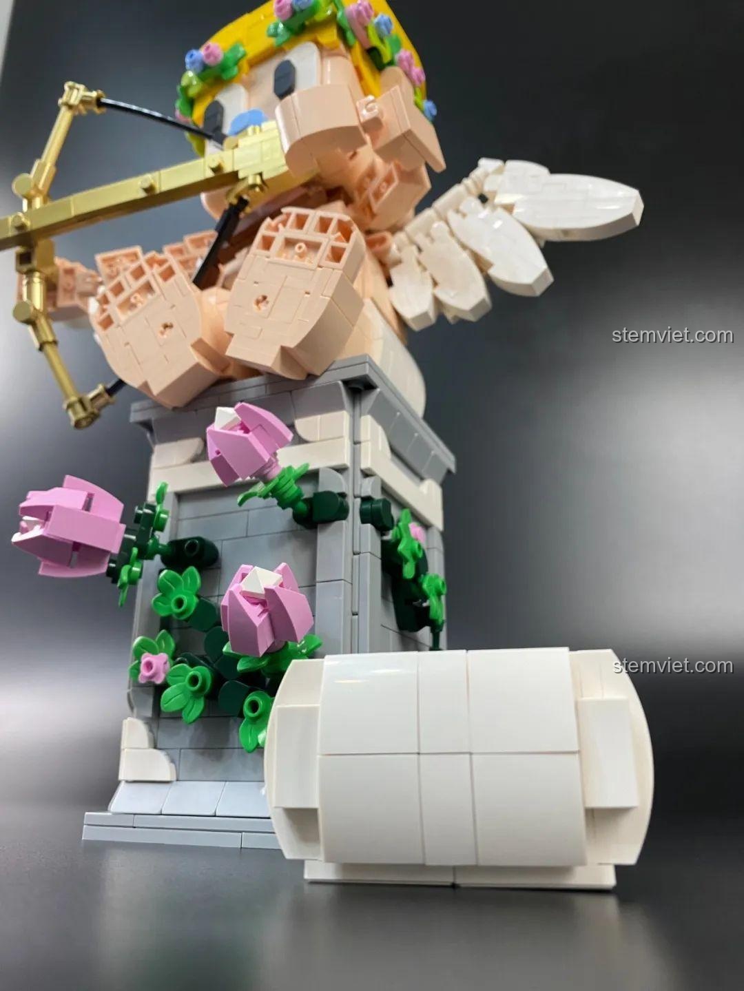 Tượng Thần Tình Yêu Cupid 846681 ngồi trên bệ, góc nhìn nghiêng, thể hiện sự cân đối và chi tiết của mô hình.