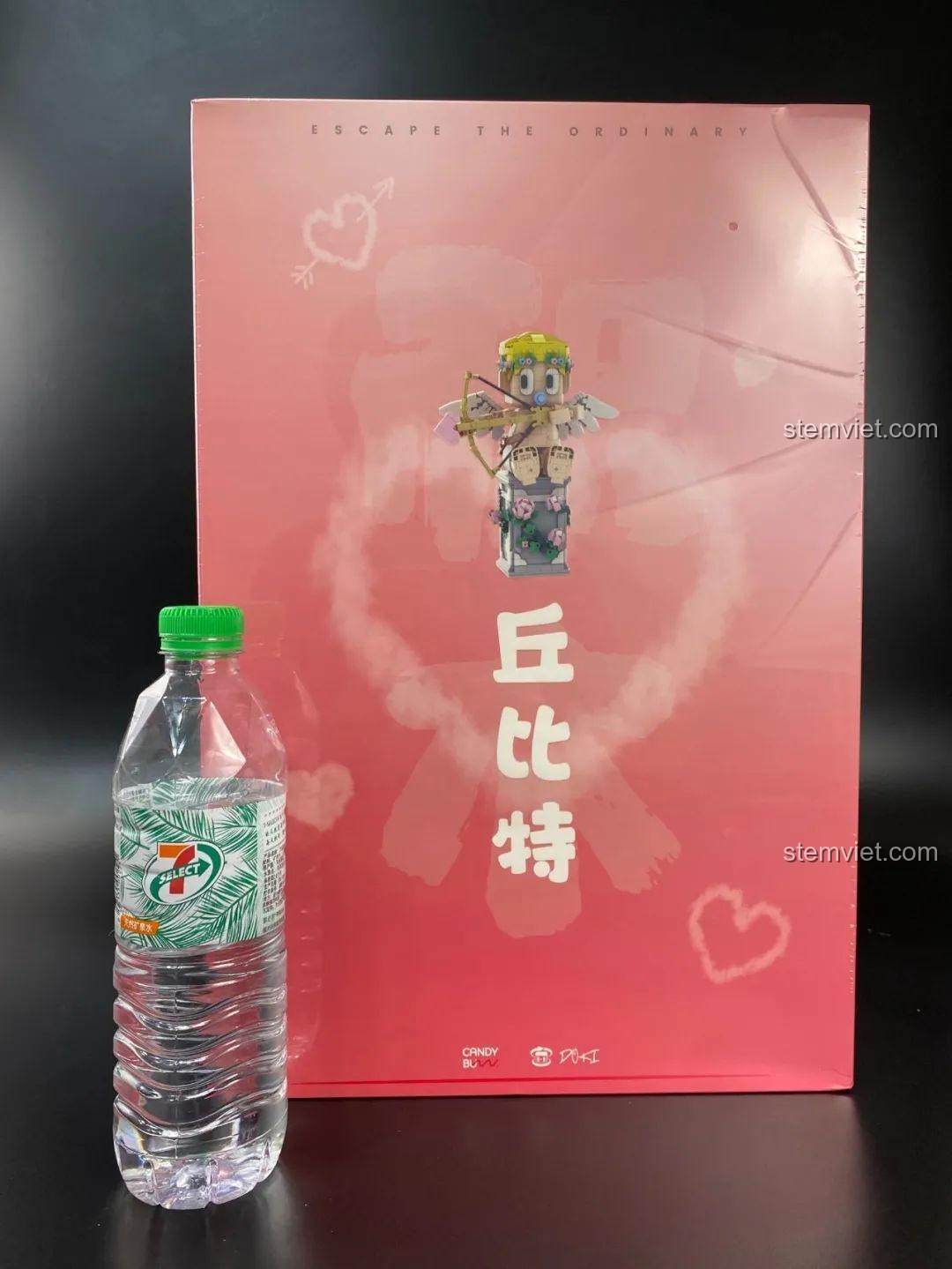 Hộp đồ chơi xếp hình DOKI 846681 Tượng Thần Tình Yêu Cupid đặt cạnh chai nước để so sánh kích thước thực tế.