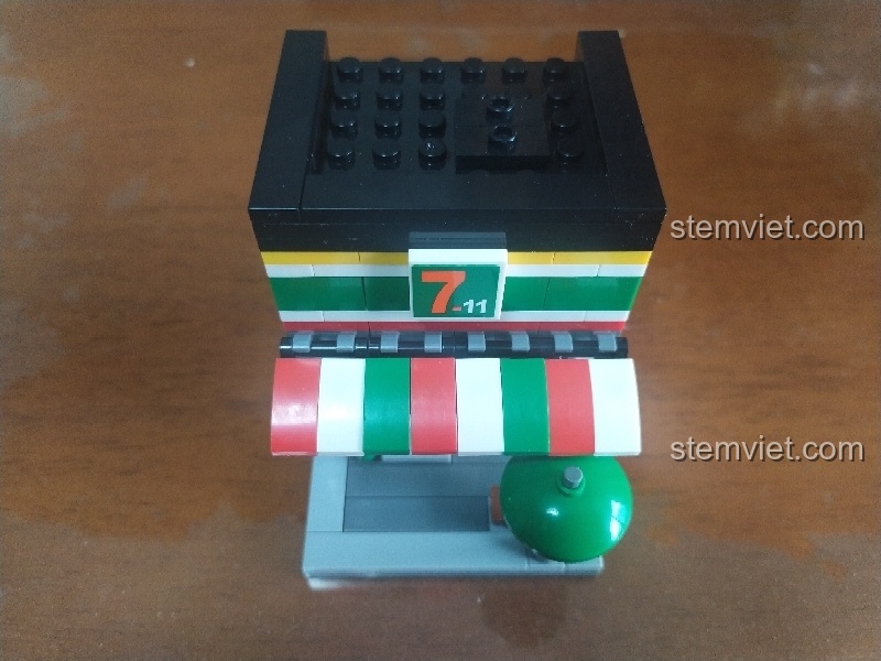 Mô hình cửa hàng tiện lợi Sembo SD6014 gần hoàn thiện với mái nhà, logo và bộ bàn ghế, dù che nắng bên ngoài.