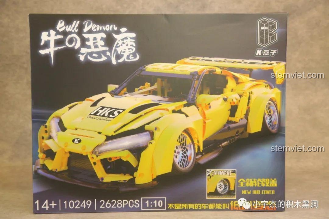 Hộp sản phẩm K Box 10249 Toyota Supra với hình ảnh mô hình xe đua màu vàng và thông số kỹ thuật.