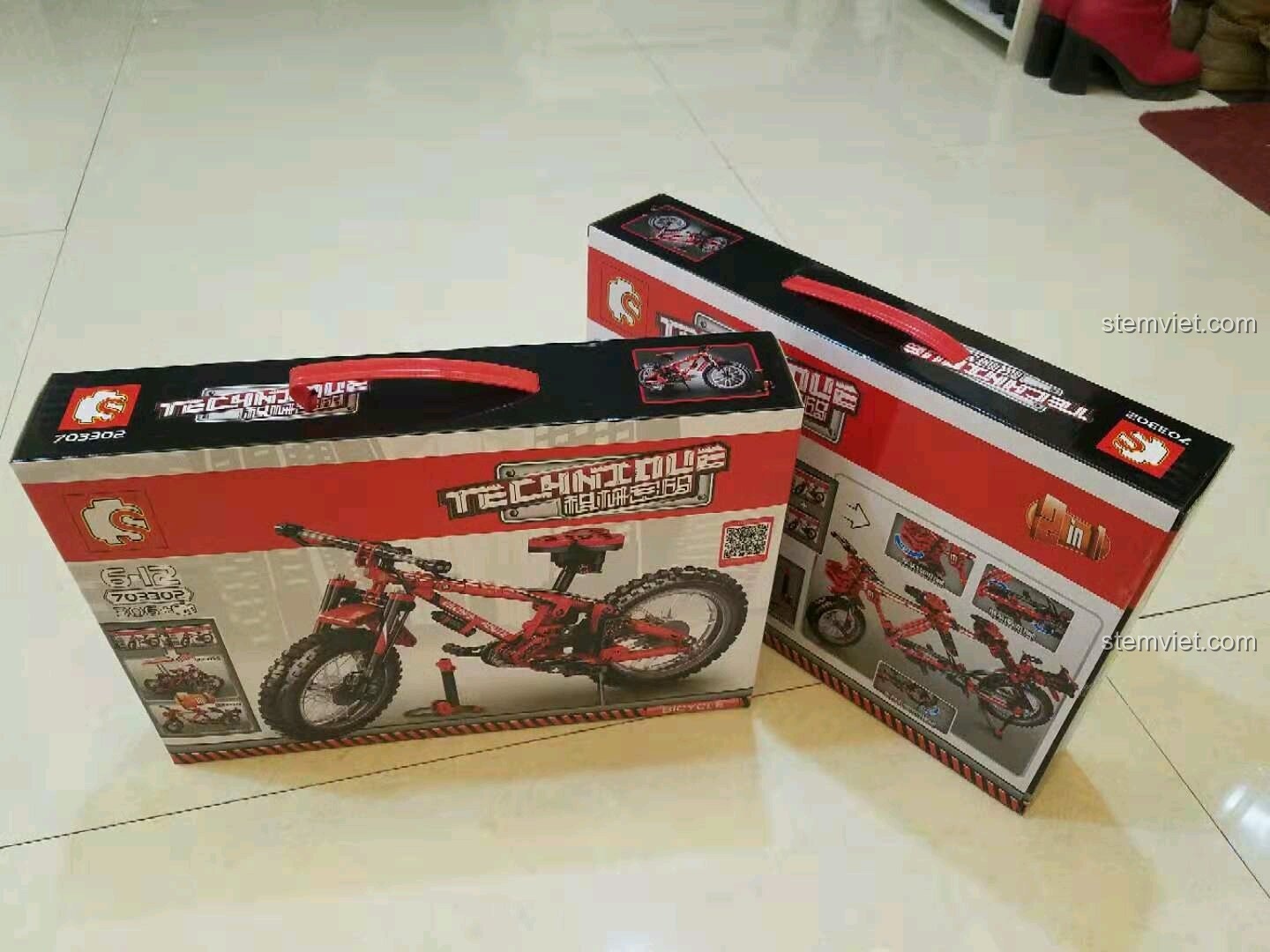 Hai hộp đồ chơi lắp ráp Sembo 703302 Xe đạp địa hình Technic màu đỏ đen đặt trên sàn nhà, sẵn sàng để được review.