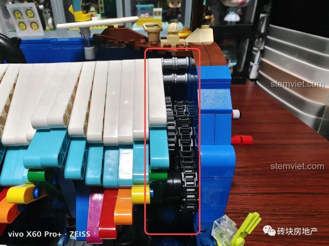 Phần hông của mô hình Hộp nhạc Mùa hè đuổi sóng để lộ bộ truyền động bánh răng và dây xích.