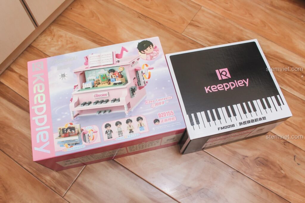 Hộp sản phẩm bộ lắp ráp Keeppley DZ0155 Đàn Piano Xoay 4 Chiều và hộp phụ kiện màu đen trên nền gỗ.