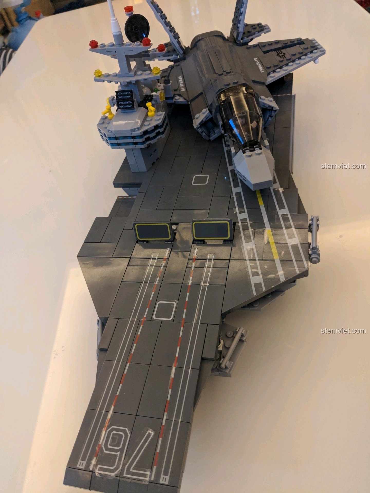 Mô hình F-35B đang chuẩn bị hạ cánh xuống mô hình tàu sân bay, góc nhìn từ phía sau máy bay.