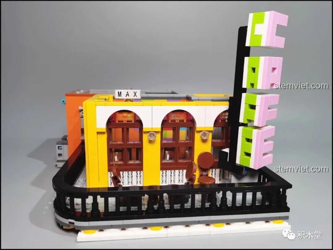 Lắp ráp biển hiệu 'CAFE' bằng các khối gạch màu hồng và xanh lá, một điểm nhấn của mô hình.