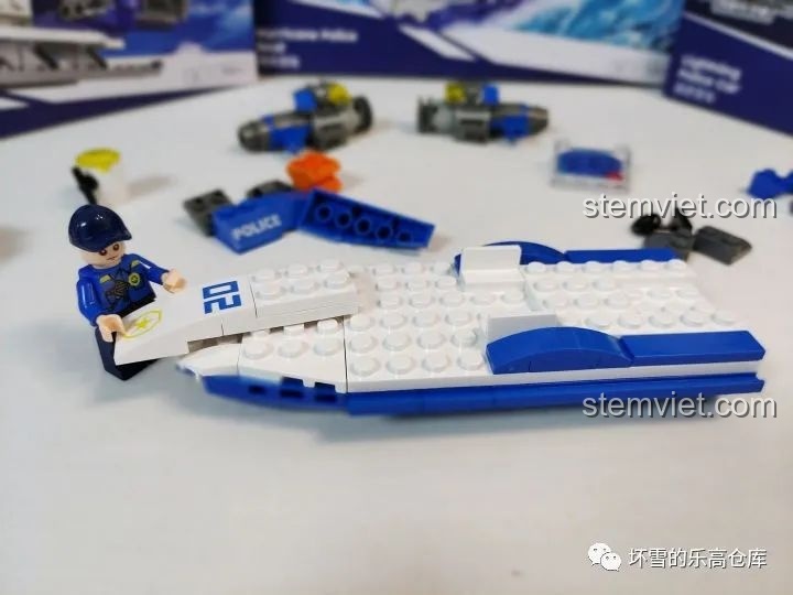 Nhân vật cảnh sát đang lắp ráp thuyền cảnh sát 'Bão Tố Biển Cả' của JAKI City Guardians, với các mảnh ghép lớn.