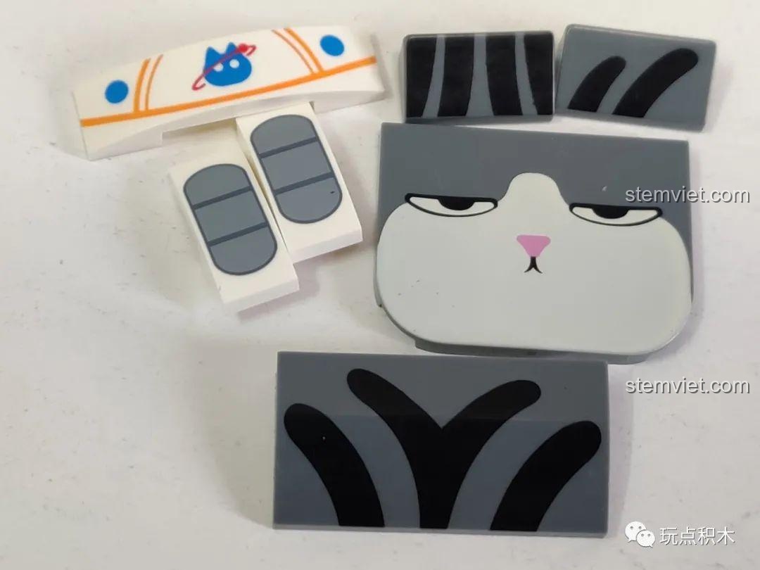 Các mảnh ghép in hình khuôn mặt, bộ đồ phi hành gia và logo mèo vũ trụ của mô hình GUDI 52052.