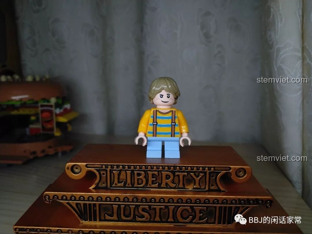 Cận cảnh minifigure khách hàng nhí trong bộ đồ chơi xây dựng Tiệm Bánh Hamburger, với áo vàng và quần yếm xanh.