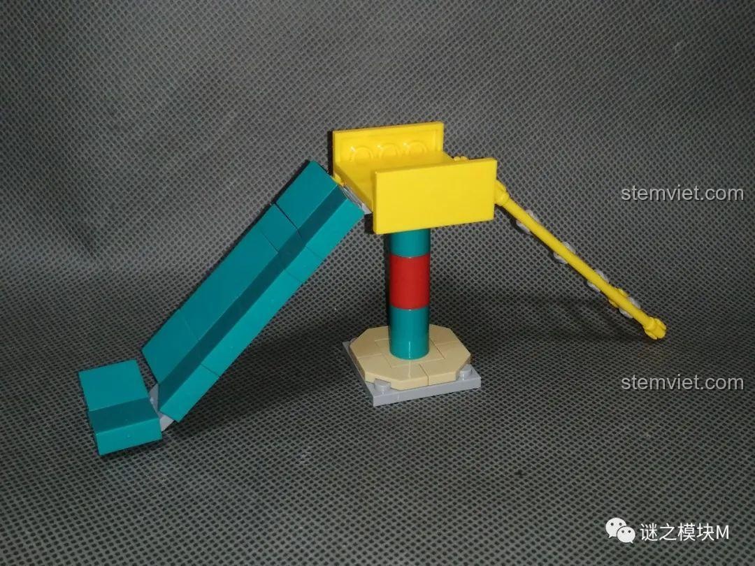 Mô hình lắp ráp cầu trượt trong sân chơi từ bộ Renzaima 102, có màu xanh và vàng.