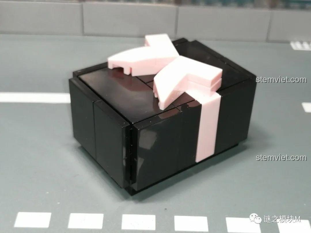 Mô hình lắp ráp chiếc quan tài màu đen với chiếc nơ màu hồng trên nắp, từ bộ Renzaima 102.