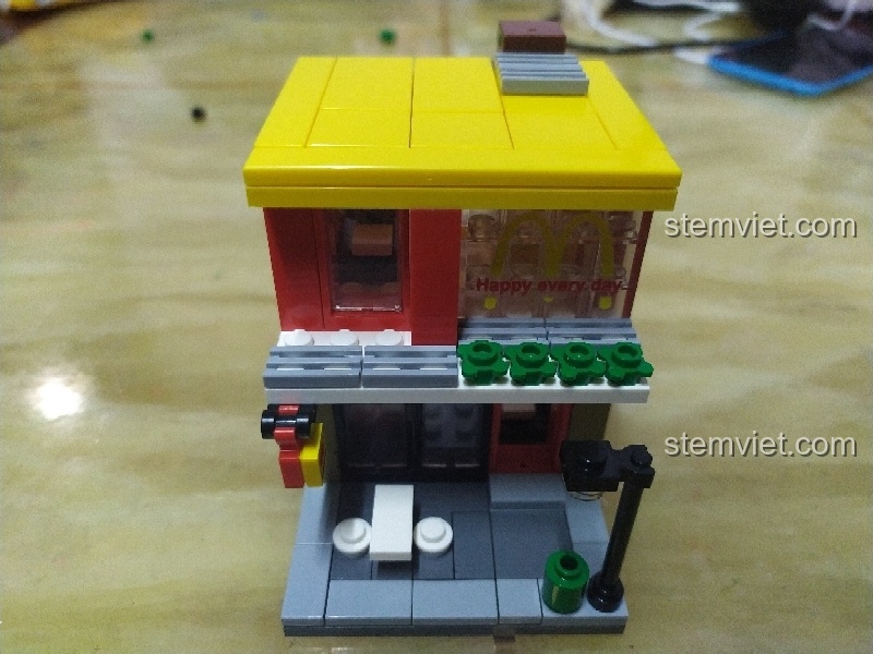 Mô hình Sembo Block SD6012 cửa hàng McDonald's hoàn chỉnh nhìn từ phía trước, với các chi tiết đèn đường và cây xanh.
