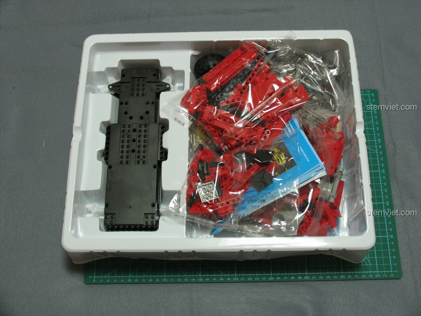 Bên trong hộp bộ lắp ráp CaDA C51005 Xe Bán Tải Đỏ với các túi linh kiện được sắp xếp gọn gàng trong khay nhựa mỏng và khung gầm xe nguyên khối.