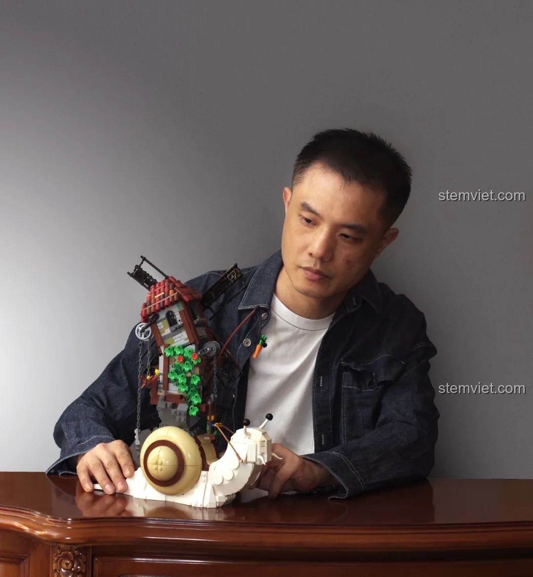 Nhà thiết kế MOC TuTuTu ngồi bên cạnh tác phẩm Cối xay gió Ốc sên độc đáo của mình, thể hiện niềm đam mê sáng tạo.