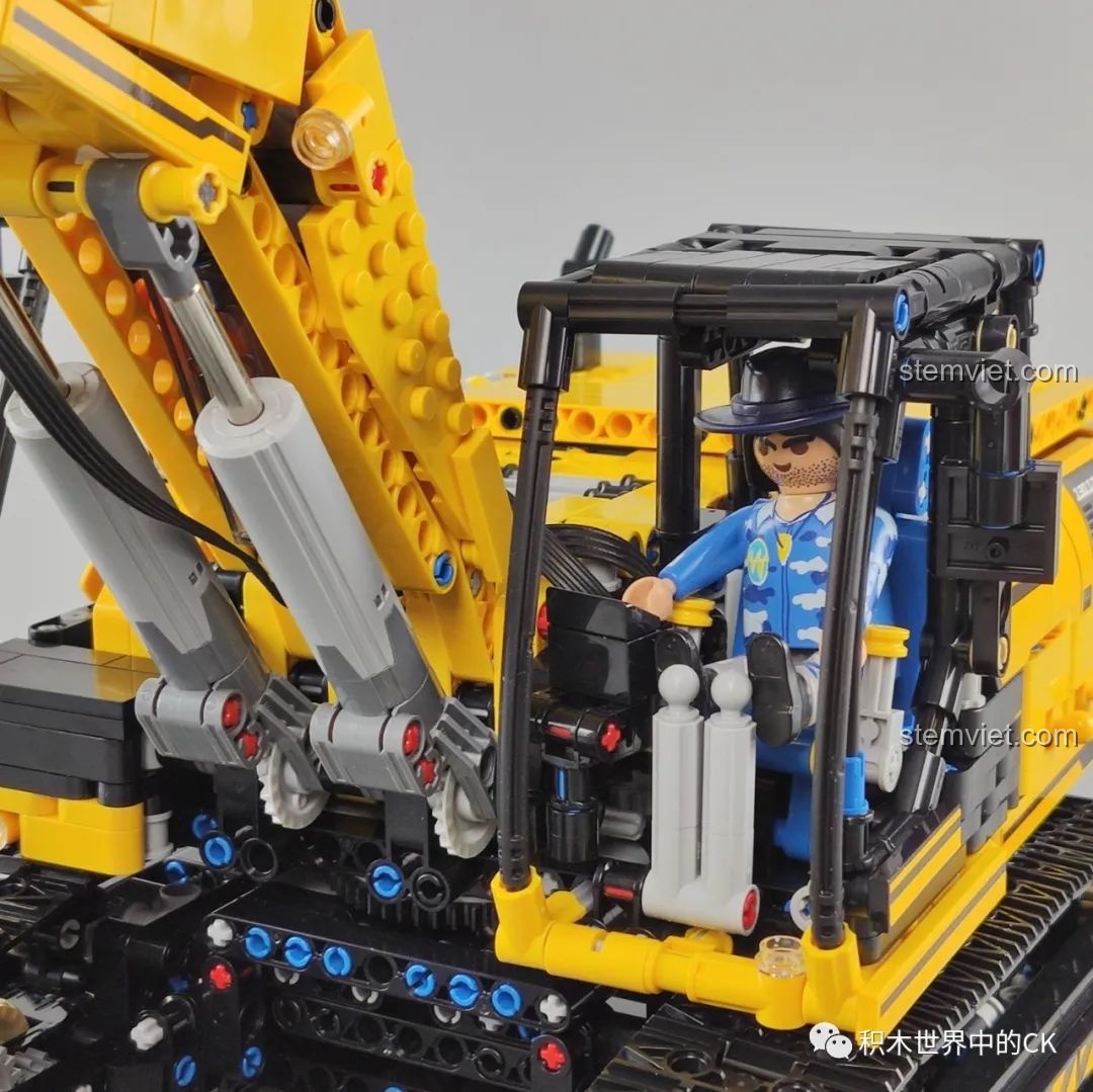 Một nhân vật đồ chơi được đặt vào trong cabin lái của máy xúc Mould King 13112 để so sánh kích thước.
