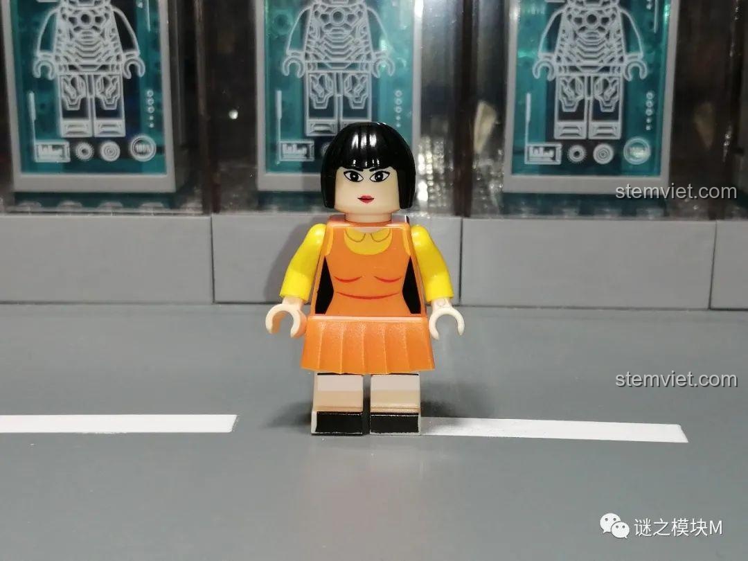 Minifigure búp bê trong trò 'Đèn xanh, đèn đỏ' từ bộ Renzaima 101, mặc váy cam và có chi tiết in ở mặt trước.