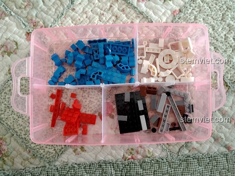 Các chi tiết của đồ chơi xây dựng Cửa Hàng Nước Ngọt Vui Vẻ được phân loại theo màu sắc trong khay đựng.