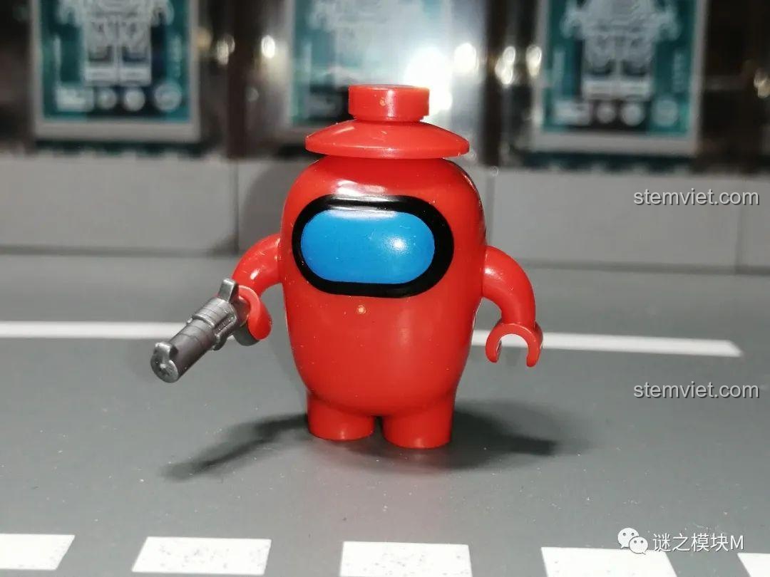 Phi hành gia Đỏ trong bộ Among Us PRCK 69702 với khẩu súng, thiết kế mắt 3D độc đáo, chất liệu nhựa ABS an toàn cho bé.