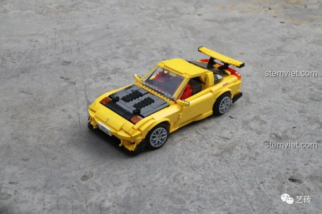 Mô hình lắp ráp CaDA C61023 Mazda RX-7 FD3S phiên bản Project D màu vàng với nắp capo đen, chụp ngoài trời trông rất sống động và chân thực.