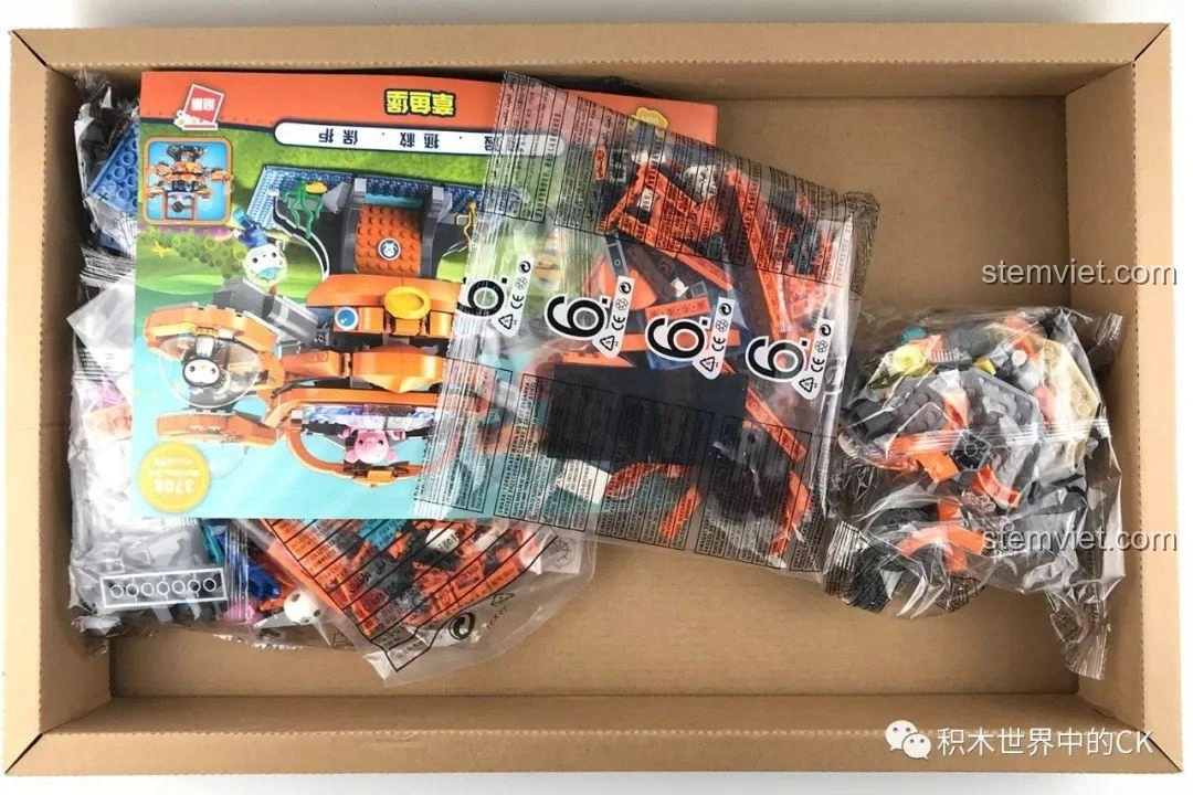 Bên trong hộp đồ chơi Enlighten 3708 Trụ Sở Bạch Tuộc Octopod với các túi mảnh ghép và sách hướng dẫn, sẵn sàng cho bé khám phá.