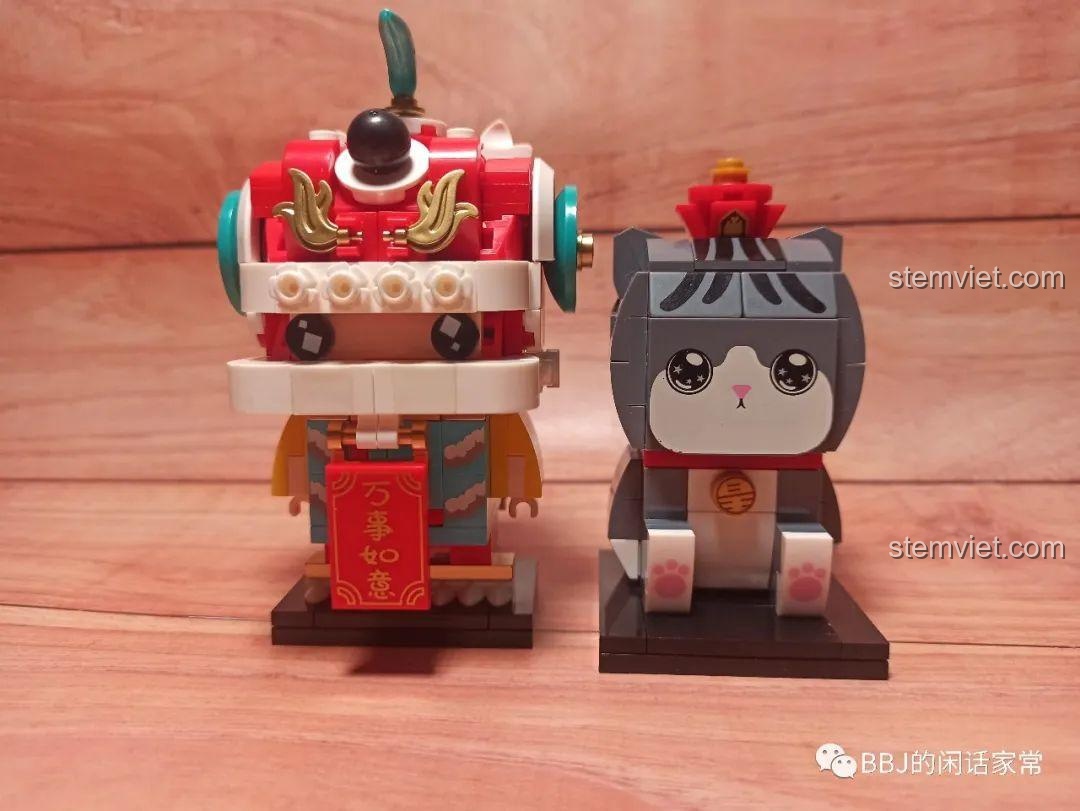 Mô hình Mèo Wuhuang Mắt Mơ Màng GUDI 52051 đứng cạnh một mô hình BrickHeadz múa lân, thể hiện sự đa dạng khi trưng bày cùng các bộ khác.