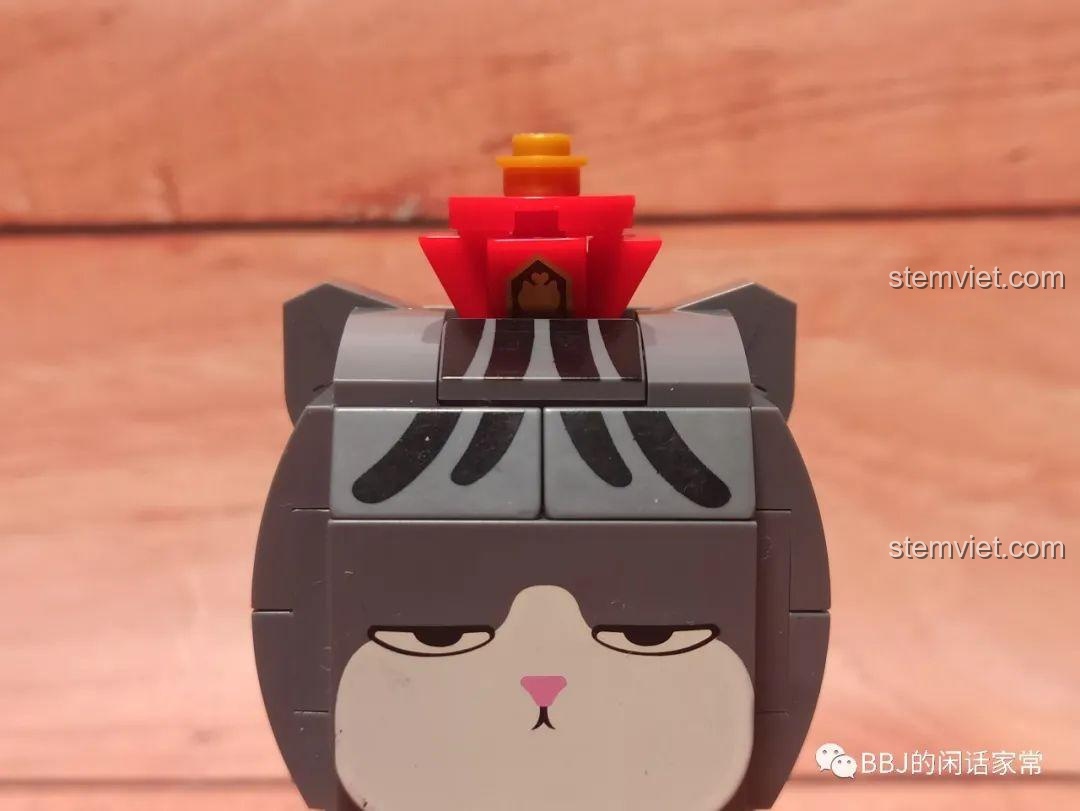 Cận cảnh chiếc vương miện màu đỏ trên đầu mô hình Mèo Wuhuang Mắt Mơ Màng GUDI 52051, với các chi tiết in ấn tinh xảo.