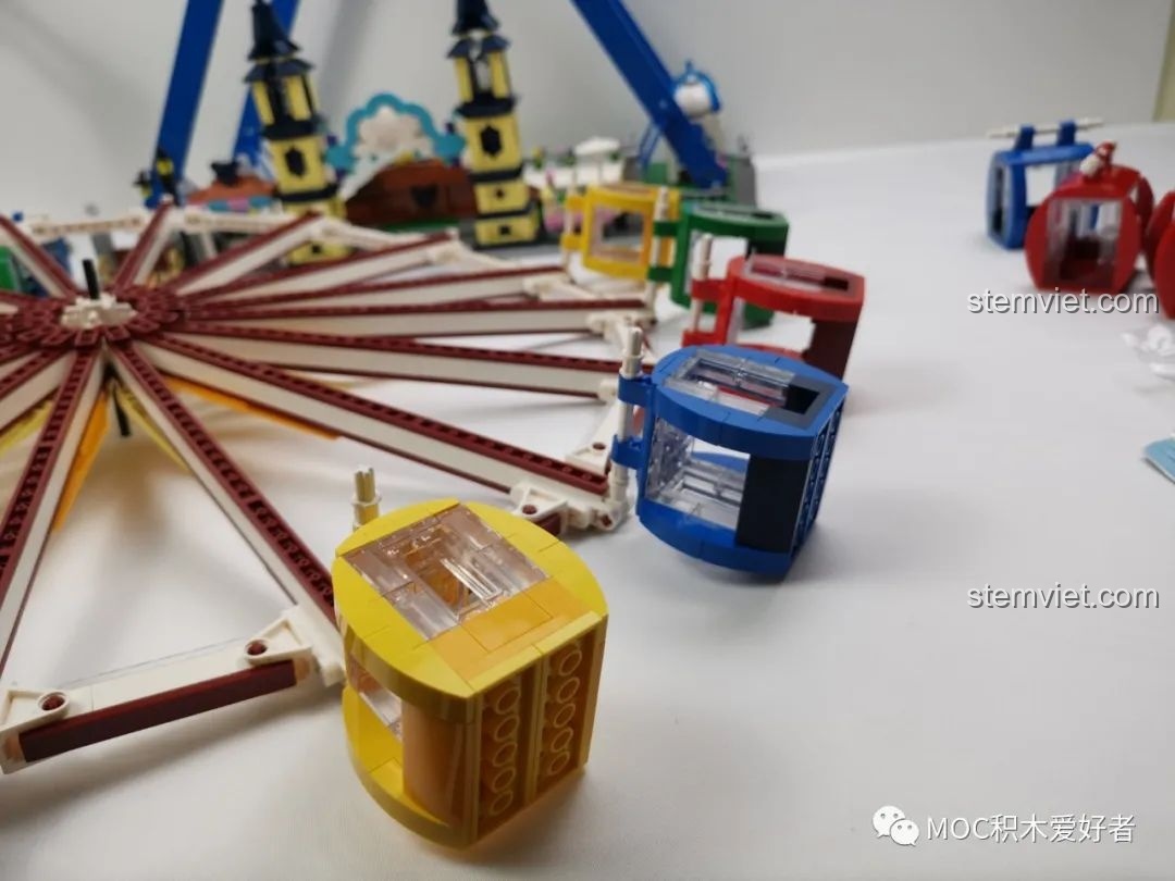 Một cabin màu vàng đang được gắn vào bánh xe của Vòng Quay Khổng Lồ Mould King 11006, các cabin khác nằm rải rác.