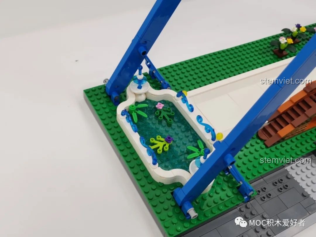 Hồ nước nhỏ với các chi tiết hoa sen và cây xanh bên cạnh khung chính của Vòng Quay Khổng Lồ Mould King 11006.