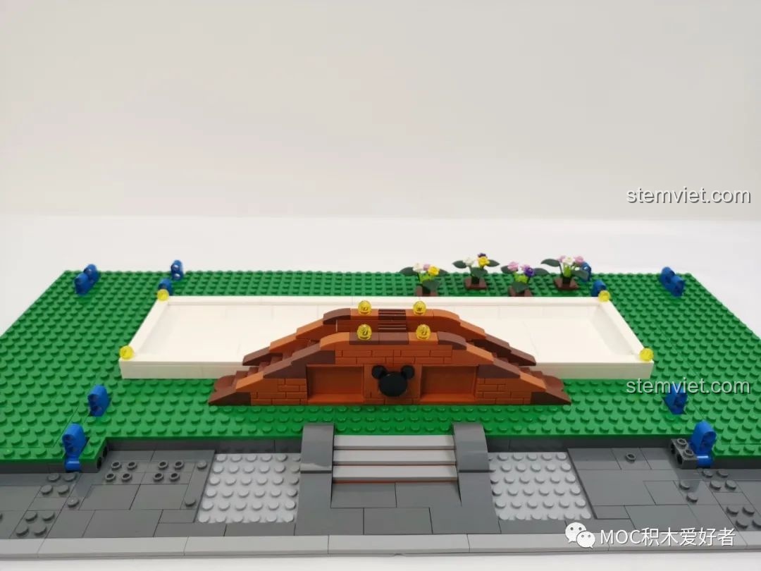 Nền tảng màu xanh lá và trắng của Vòng Quay Khổng Lồ Mould King 11006 đang được lắp ráp, với cầu và hoa trang trí.