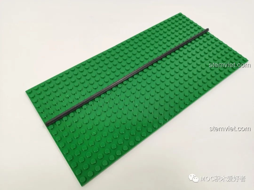 Trục carbon dài 32cm màu đen đặt trên tấm đế xanh lá, một chi tiết quan trọng của Vòng Quay Khổng Lồ Mould King 11006.