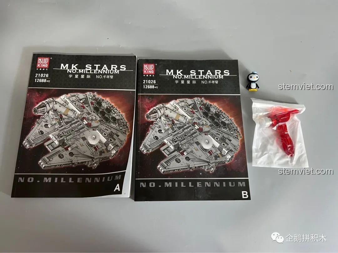 Hai cuốn sách hướng dẫn lắp ráp A và B của Tàu Thiên Niên Kỷ Mould King 21026, cùng với một chiếc búa nhỏ đi kèm, hỗ trợ quá trình lắp ráp.