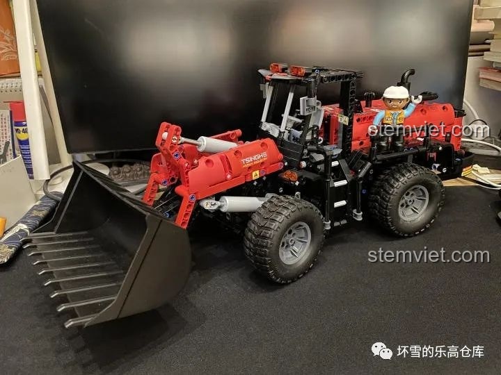 Một em bé đang chơi với gầu xúc của mô hình Xe Xúc Lật Công Trình ONEBOT OBZZJ01AIQI, thể hiện tính tương tác.