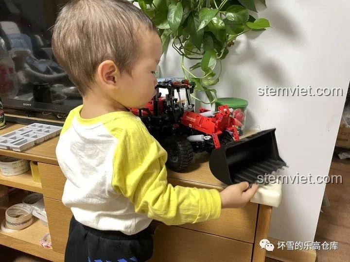 Một em bé đang tương tác với mô hình Xe Xúc Lật Công Trình ONEBOT OBZZJ01AIQI, thể hiện độ bền và khả năng chơi.