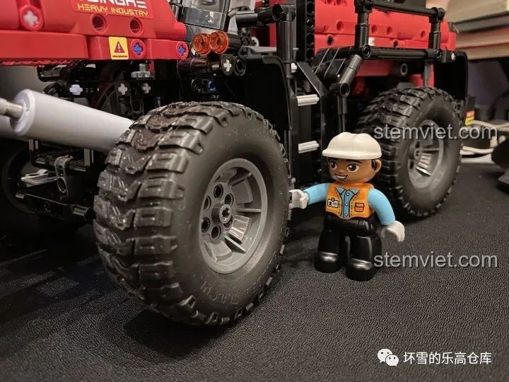 Lốp xe hầm hố của Xe Xúc Lật Công Trình ONEBOT OBZZJ01AIQI với nhân vật minifig đứng cạnh, cho thấy kích thước.
