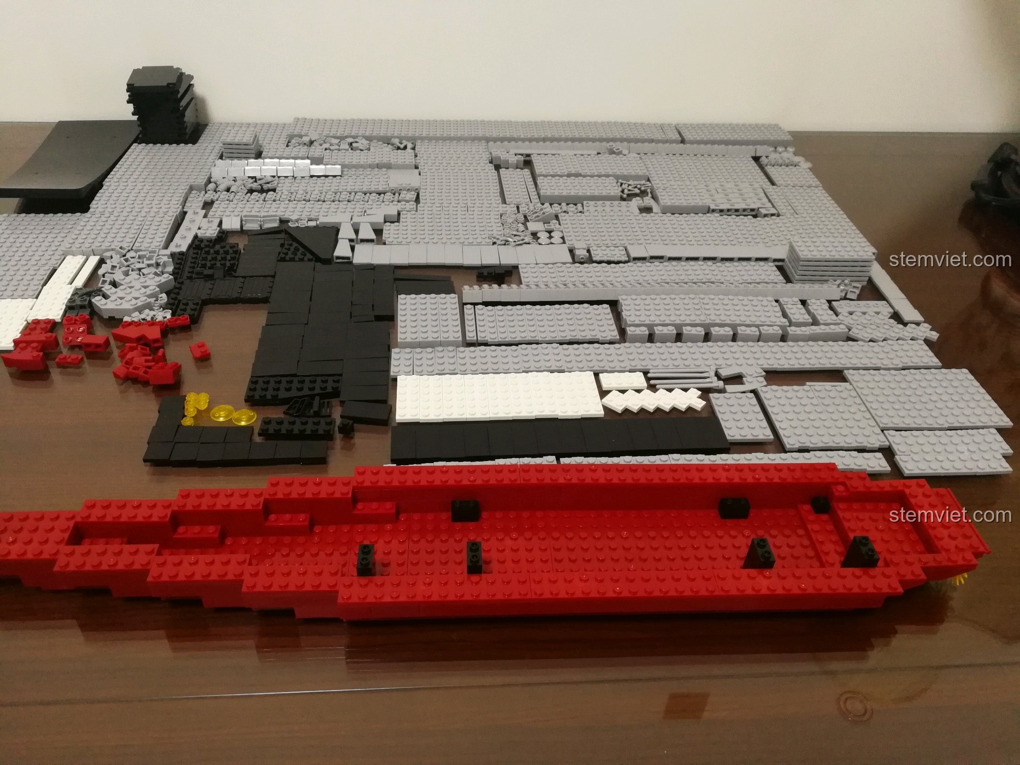 Các mảnh ghép màu đỏ và xám của bộ Sluban 399 Mô hình tàu sân bay Liêu Ninh được xếp chồng lên nhau, dần hình thành phần thân dưới của tàu chiến.