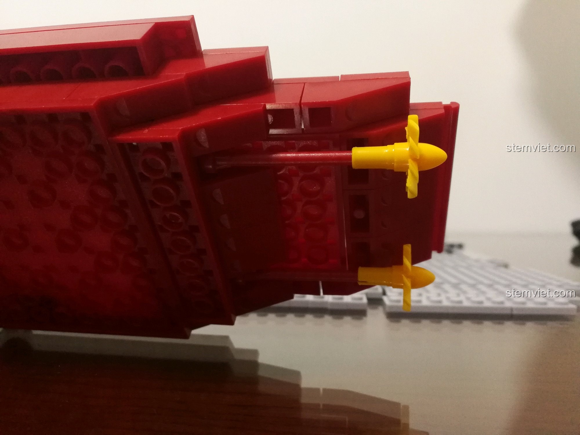 Góc nhìn từ trên cao xuống phần thân dưới của bộ lắp ráp Sluban 399 Mô hình tàu sân bay Liêu Ninh đang được xây dựng, với các mảnh ghép màu đỏ và xám được kết nối.