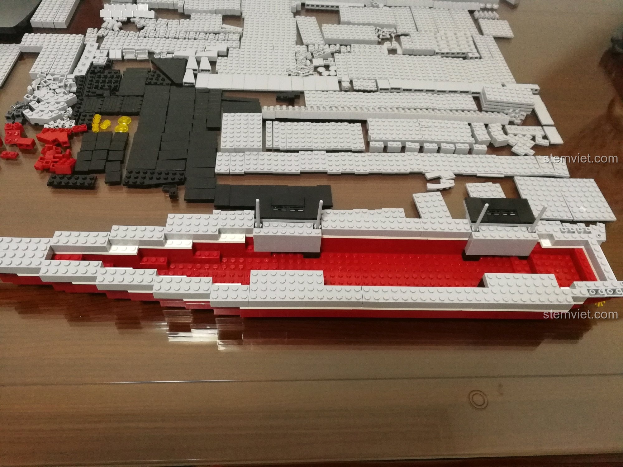 Phần thân dưới của bộ lắp ráp Sluban 399 Mô hình tàu sân bay Liêu Ninh đang được hoàn thiện với các lớp mảnh ghép màu trắng và đỏ, tạo nên đường viền của tàu.