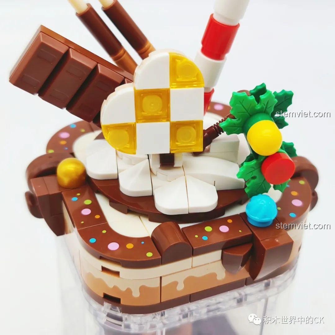 Cận cảnh phần kem trang trí trên mô hình SEMBO 615012 Cốc Kem Socola Hạnh Phúc, với thanh socola và kẹo gậy. Đồ chơi lắp ráp đẹp mắt.