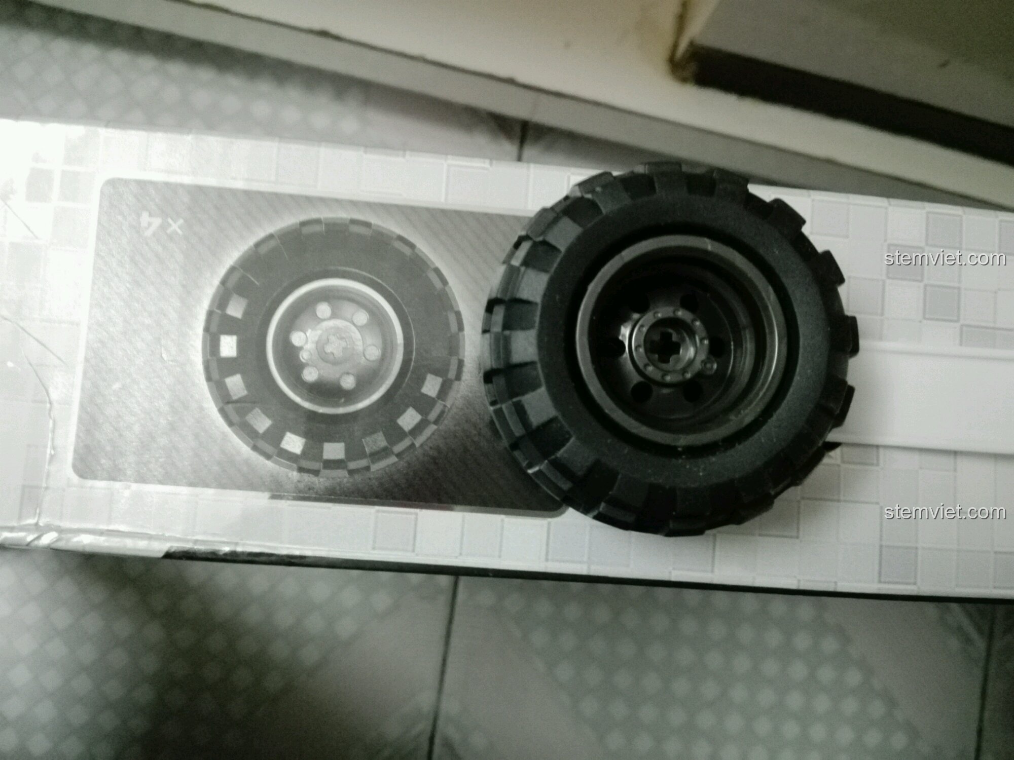 Cạnh hộp đồ chơi xây dựng XB 03025 với hình ảnh bánh xe tỉ lệ 1:1 để so sánh kích thước thực tế.